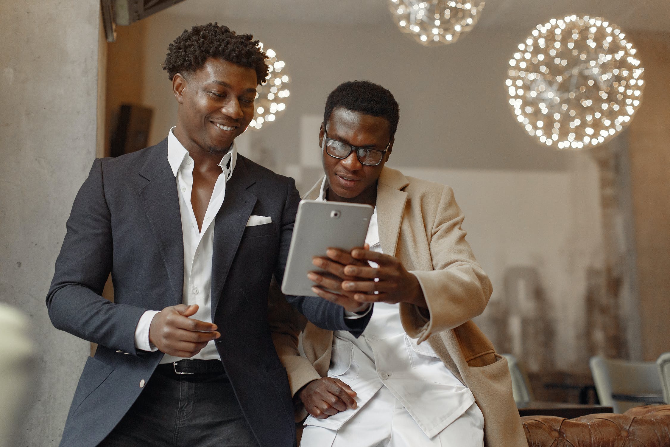 Two men in suits looking at a tablet